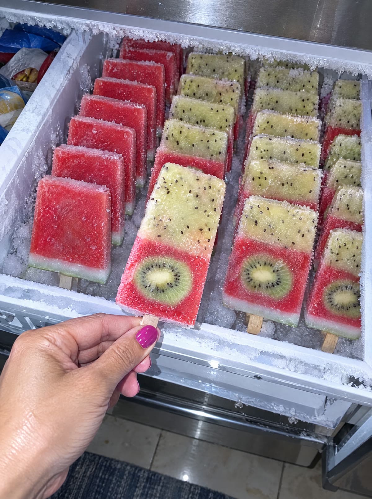 A freezer drawer packed with rows of pops.